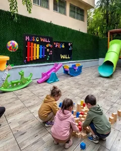 Bağcılar Öyküm Anaokulu bahçesinde müzik duvarı, kaydırak ve ahşap bloklarla oynayan çocuklar